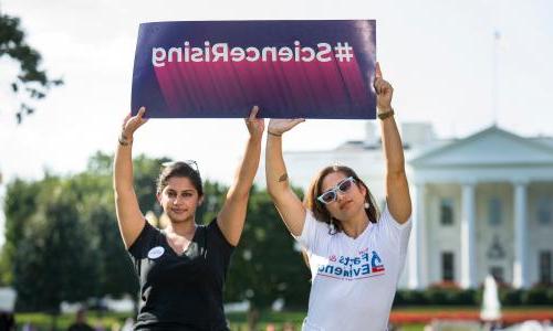 Two women holding a sign that says "617888九五至尊娱乐不断上升"